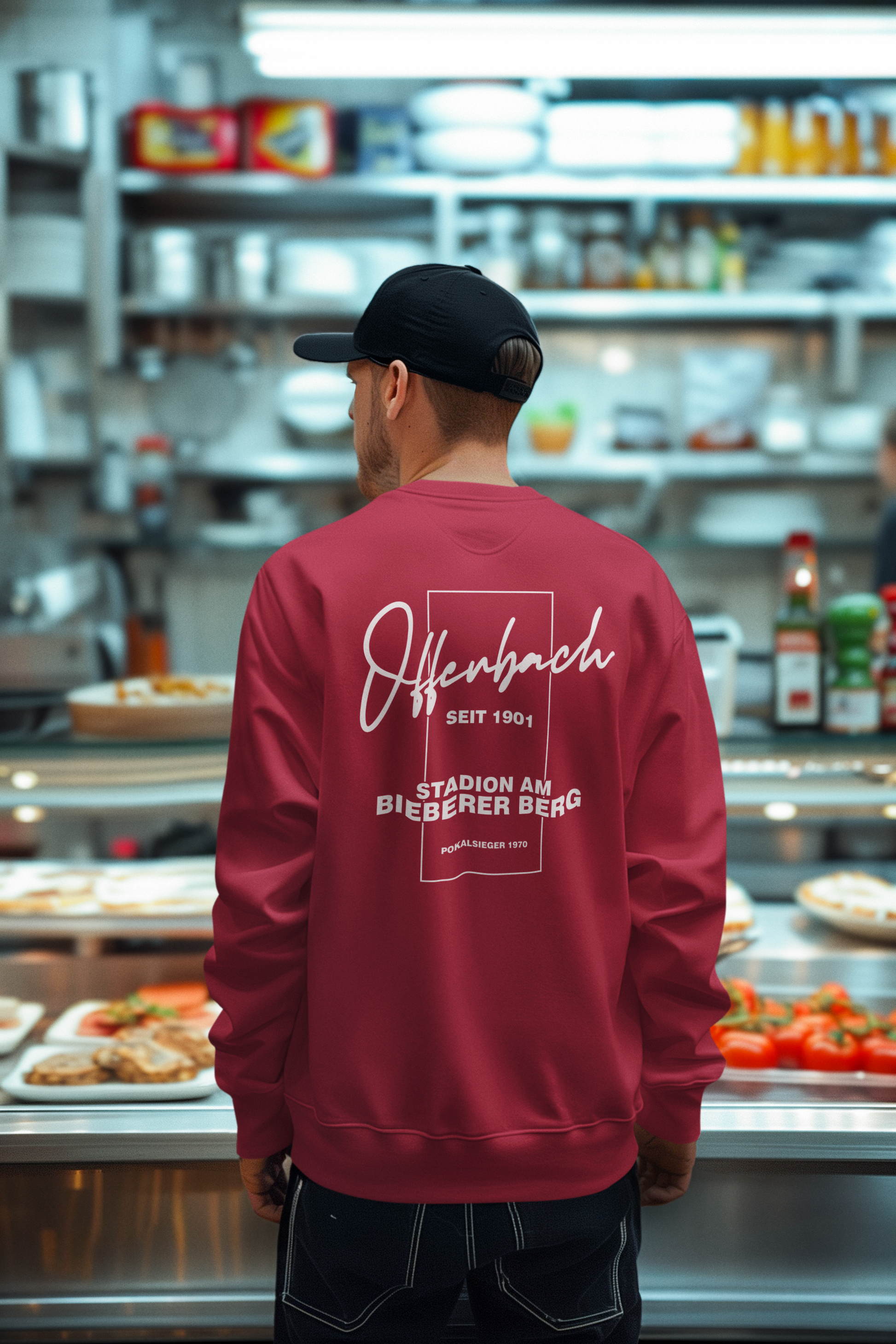Bordeauxrotes OFCast Sweatshirt mit Rückenprint „Offenbach – Stadion am Bieberer Berg“, getragen in Kantinenszene